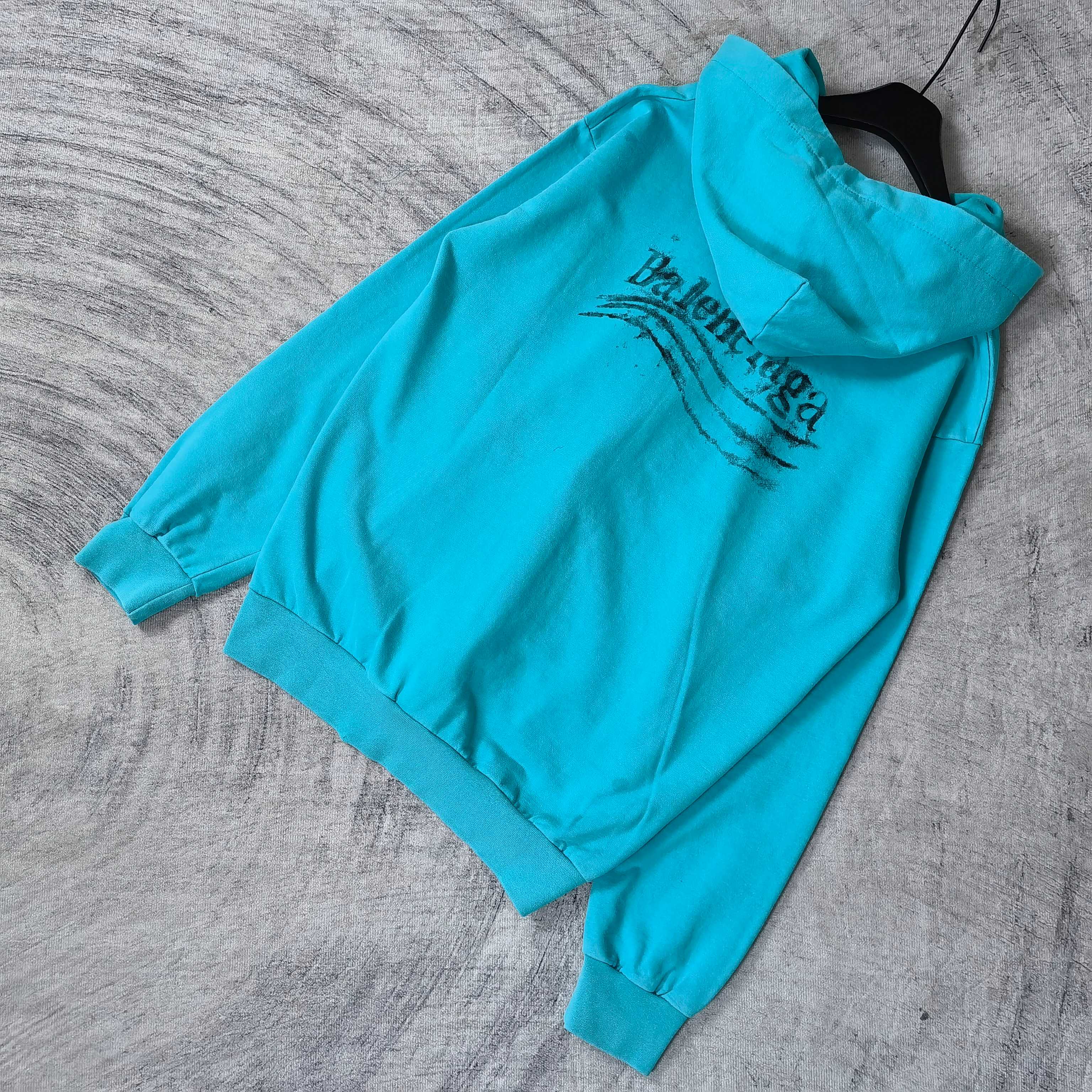 Turquoise zip-up hoodie with hood and Balenciaga logo across back, side view