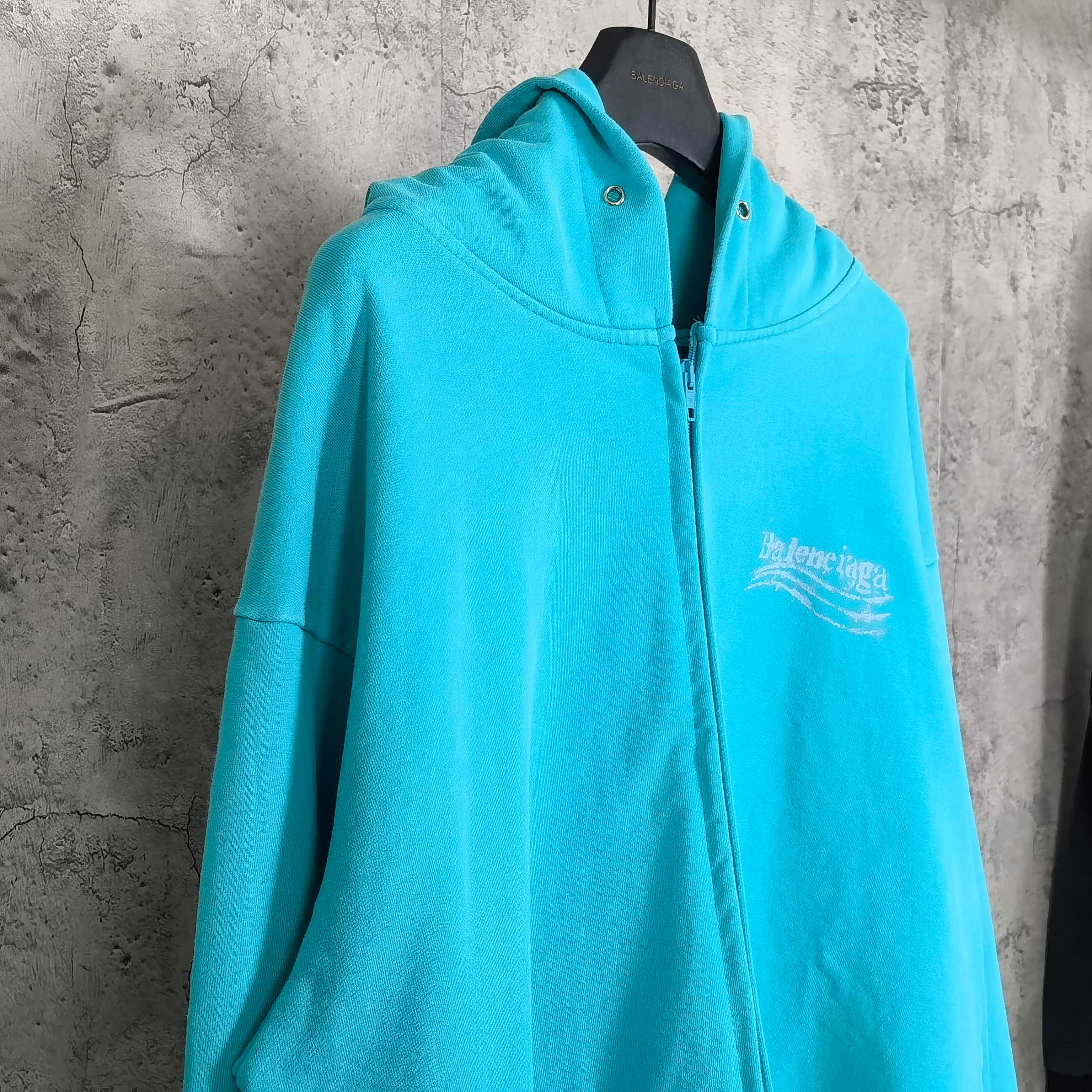 Turquoise zip-up hoodie with hood and Balenciaga chest logo, front view