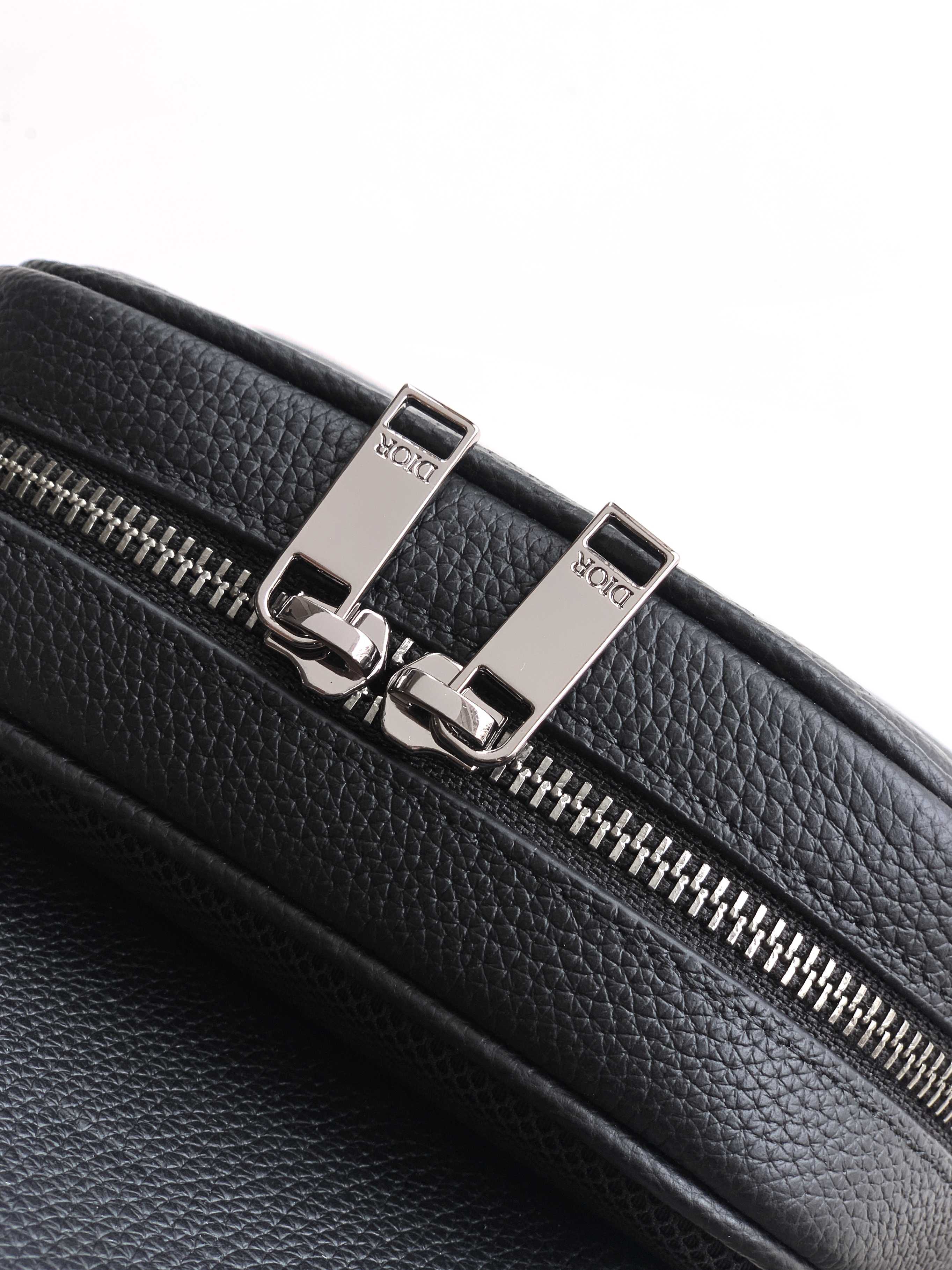 Dior mini bag zipper detail, black pebbled leather with metal pull and 'Dior' markings