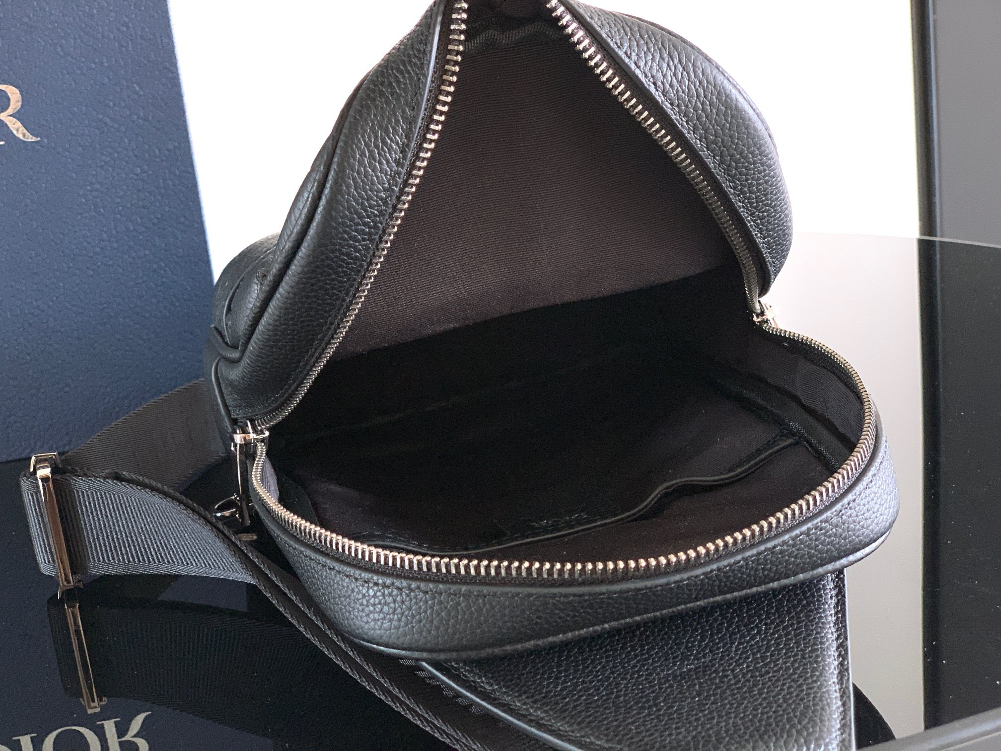 Dior mini bag, black leather interior visible, zip closure with gold trim