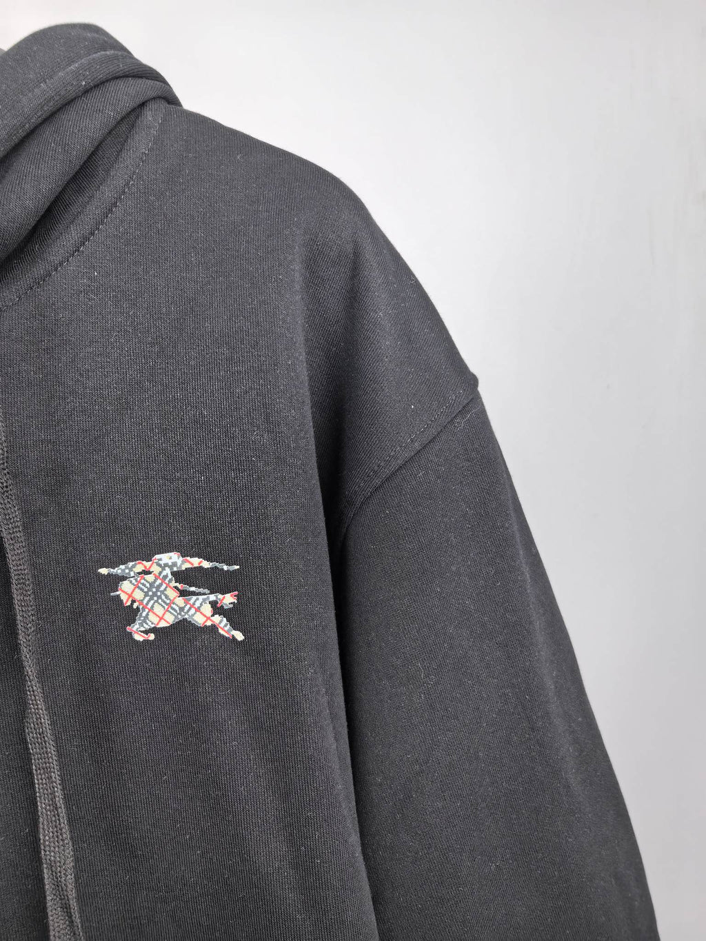 Black hoodie sleeve with small multicolor logo patch embroidery on the side.