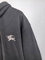 Black hoodie sleeve with small multicolor logo patch embroidery on the side.