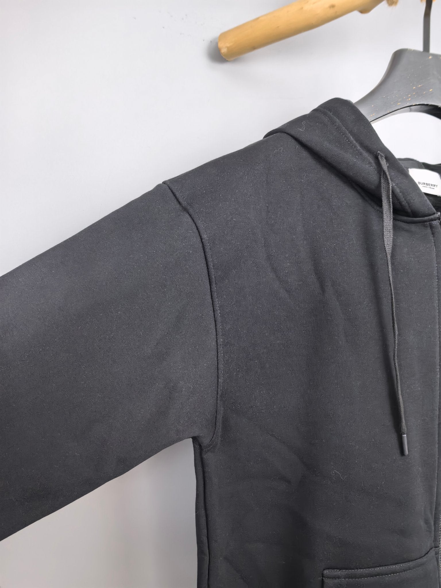 Black hoodie side view with drawstring hood and kangaroo pocket at the front.