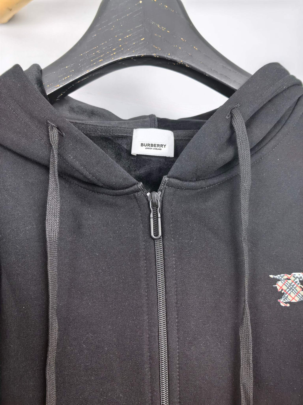 Black zip-up hoodie hood with drawstrings and close-up of the front zipper area.