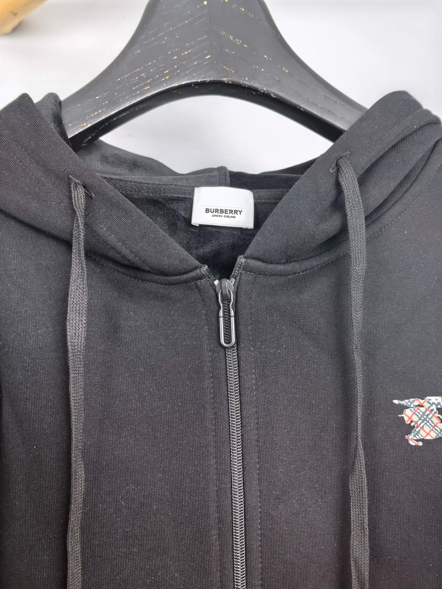 Black zip-up hoodie hood with drawstrings and close-up of the front zipper area.