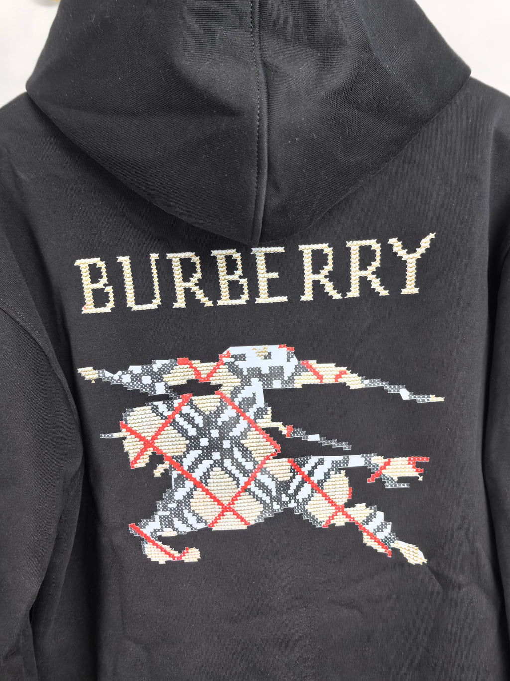 Black hoodie with Burberry lettering across the hood and large plaid graphic print.