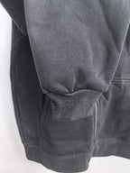 Black hoodie with ribbed knit cuff at the sleeve and textured fabric hem area.