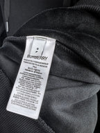 Inside hood neck label on black hoodie fabric with Burberry branding.