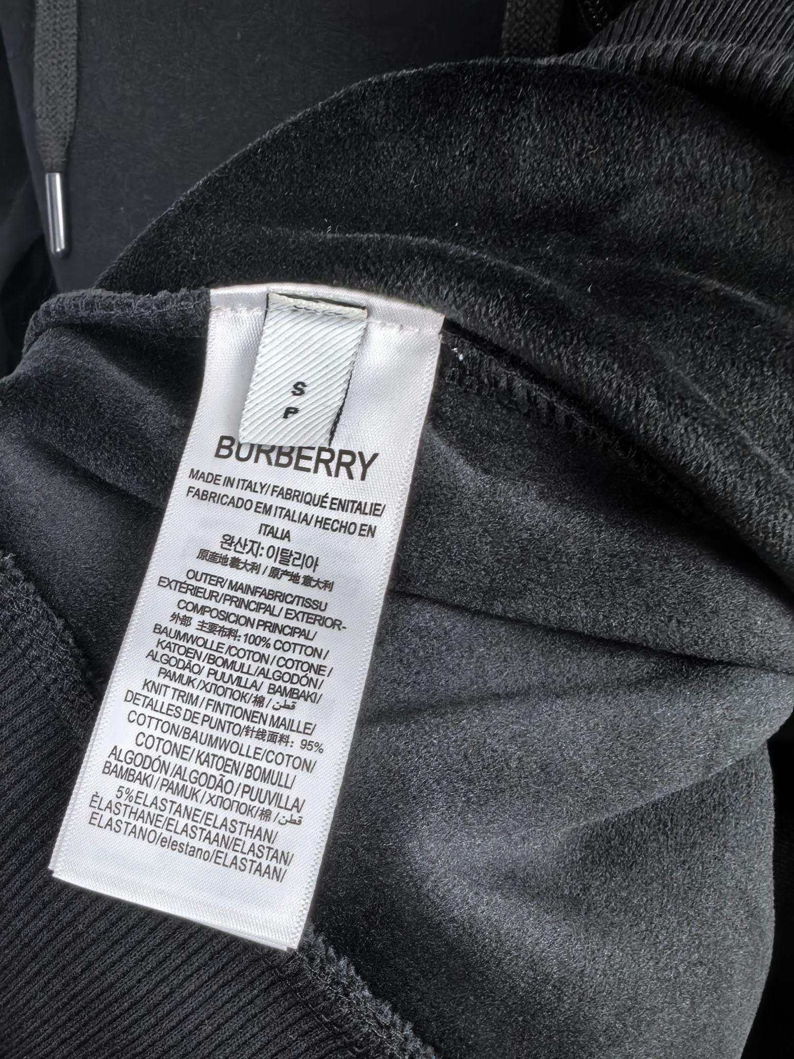 Inside hood neck label on black hoodie fabric with Burberry branding.