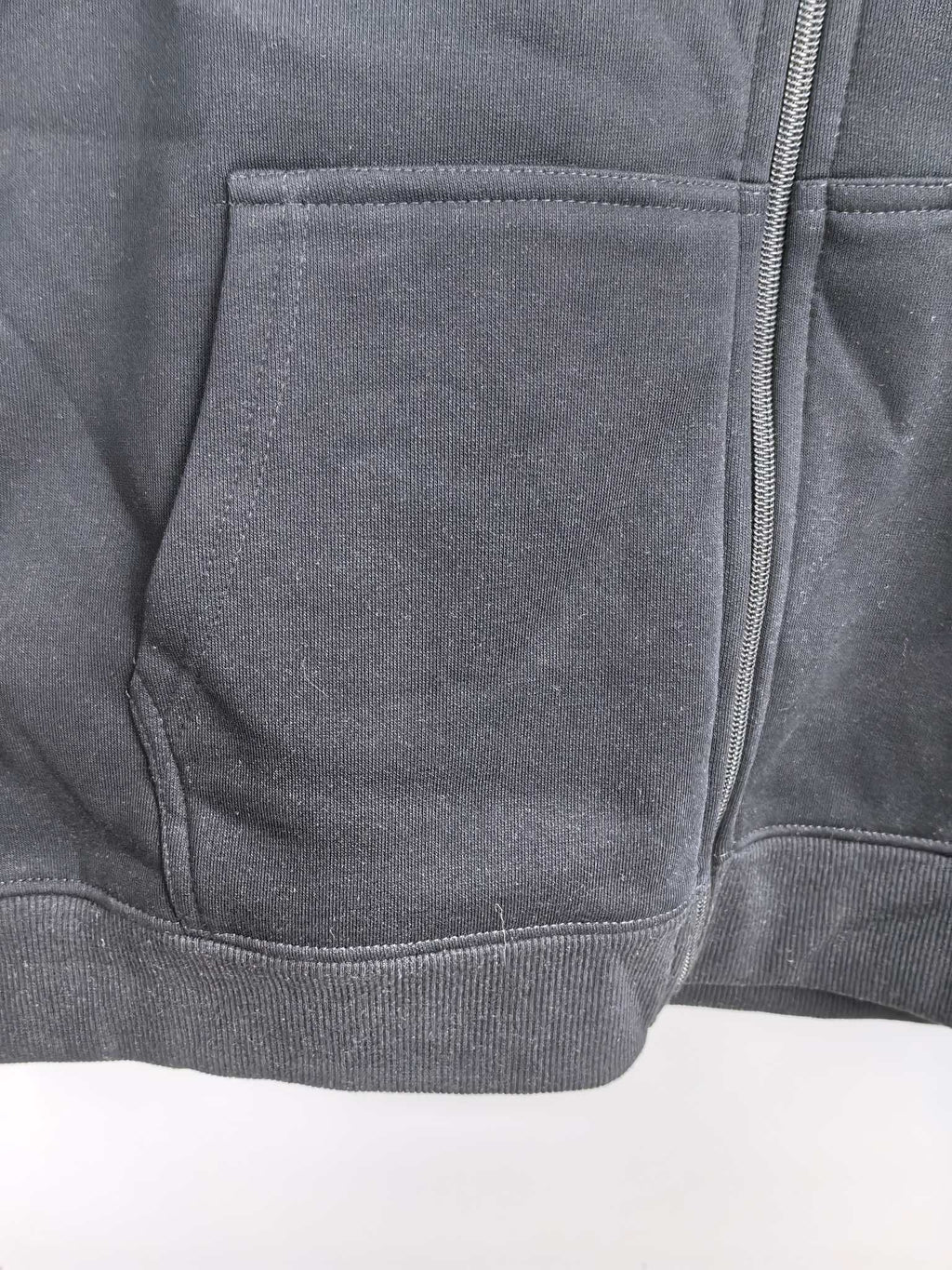 Black hoodie with stitched pocket panel and visible front zipper seam.