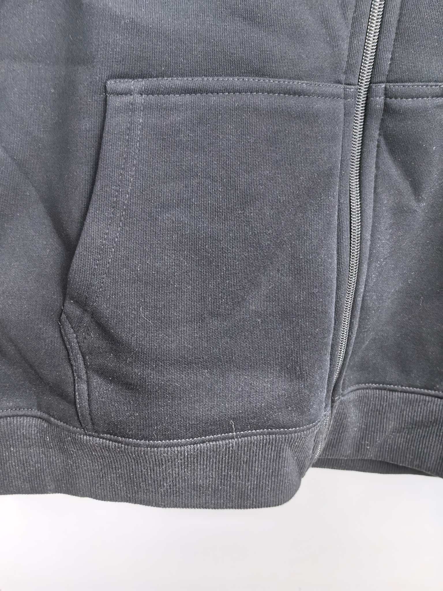 Black hoodie with stitched pocket panel and visible front zipper seam.