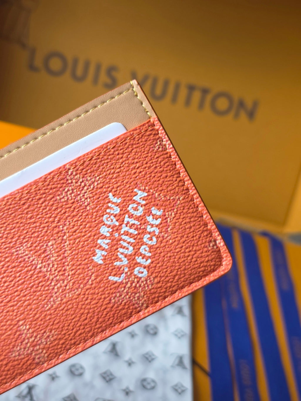 Coral textured Louis Vuitton card holder detail with white logo print