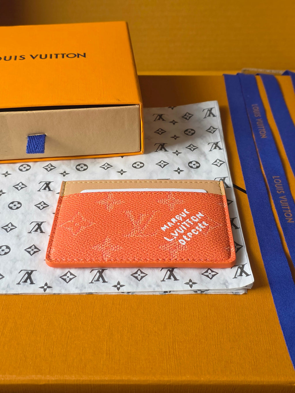 Small Louis Vuitton cardholder, coral orange monogram leather with beige edge trim and slot.