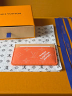 Small Louis Vuitton cardholder, coral orange monogram leather with beige edge trim and slot.