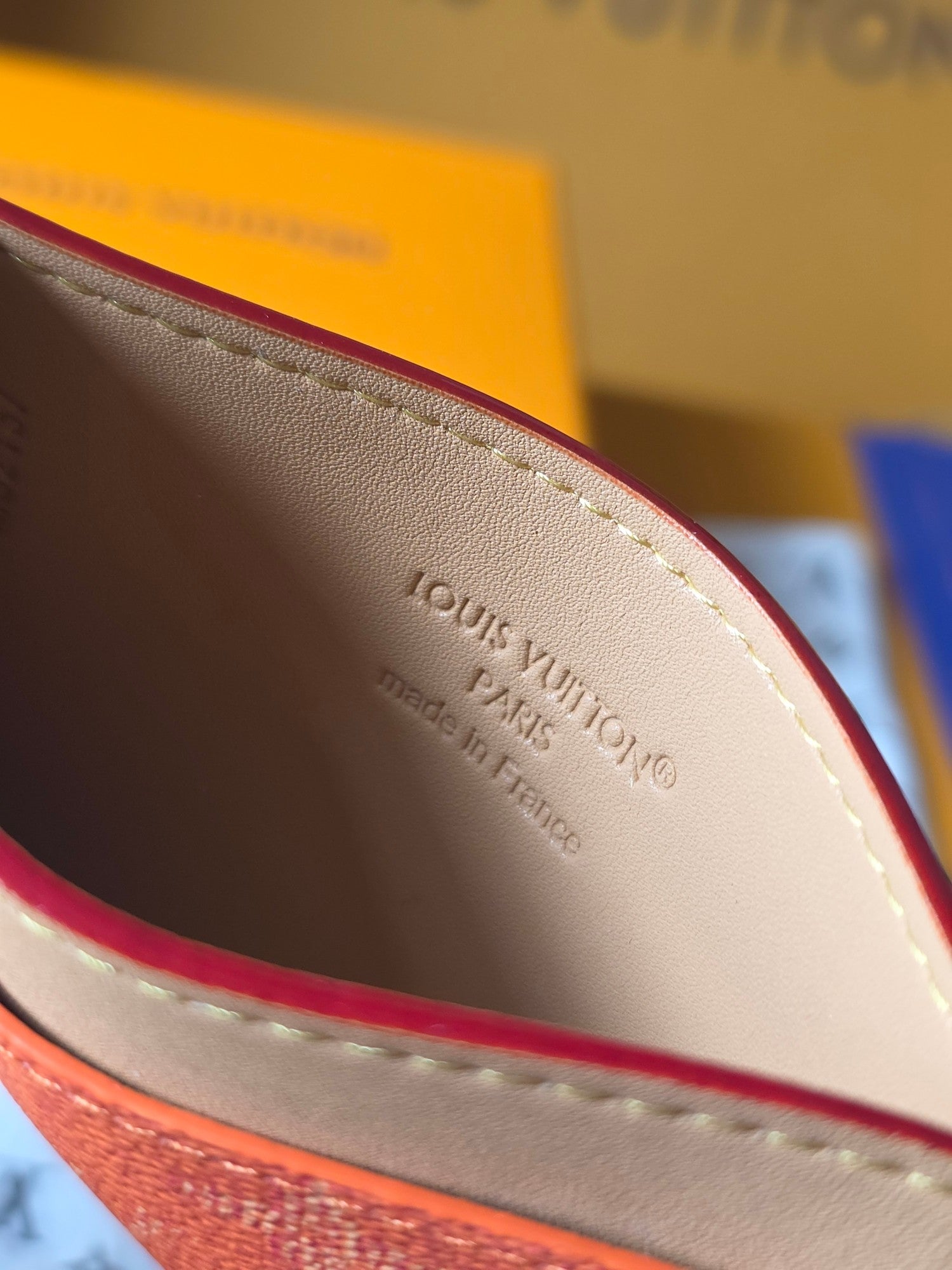 Small Louis Vuitton cardholder interior close-up with beige lining and embossed logo stamp.