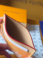 Small tan Louis Vuitton monogram bag opened, showing dark interior and white card slot