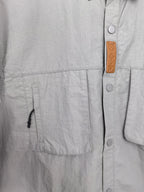 Gray jacket front with brown branded leather patch and metal snaps