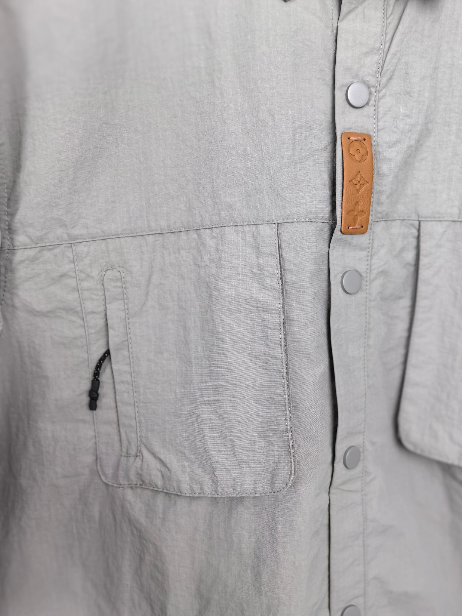 Gray jacket front with brown branded leather patch and metal snaps