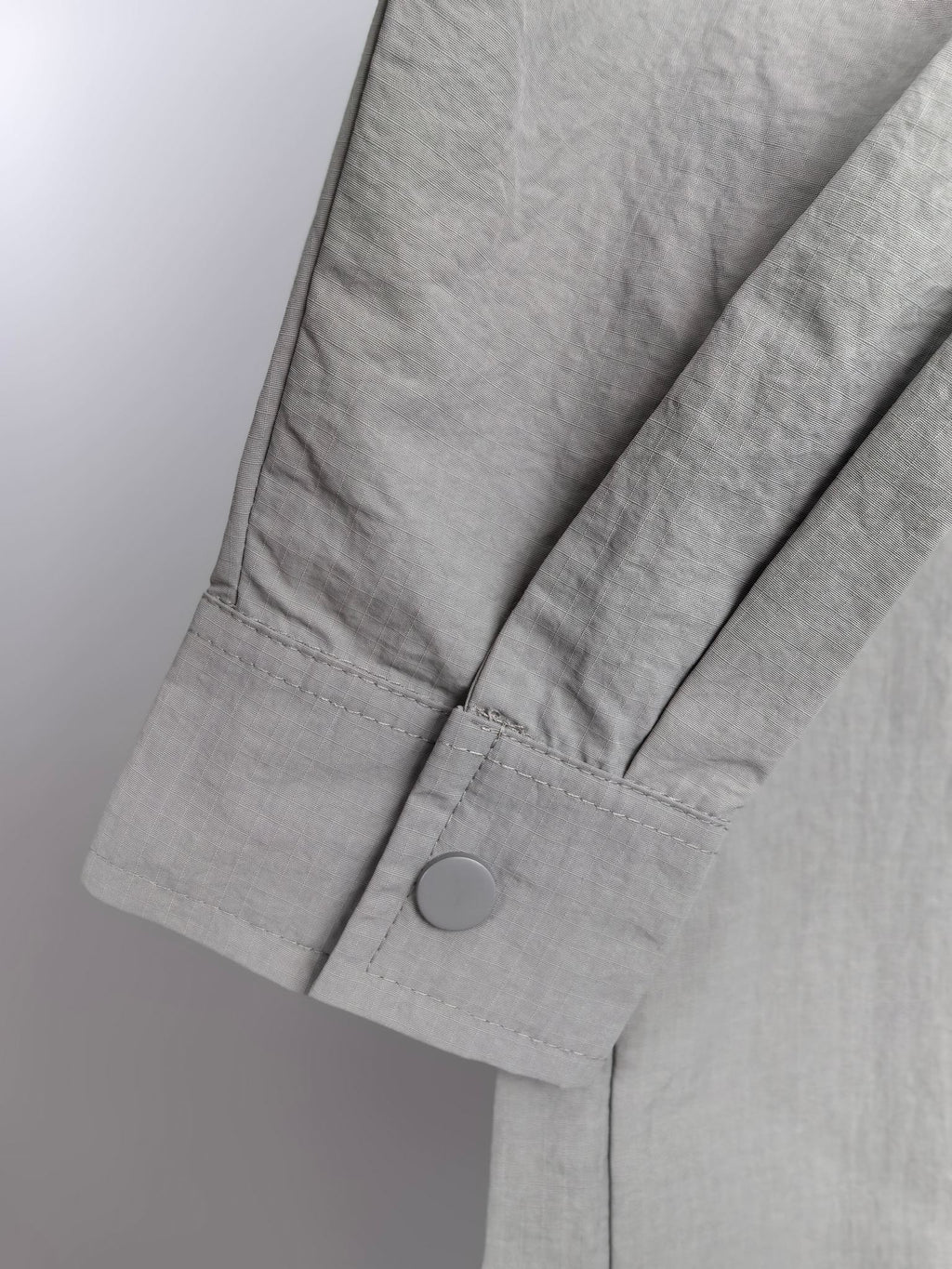 Gray jacket sleeve with buttoned cuff and structured seam detail