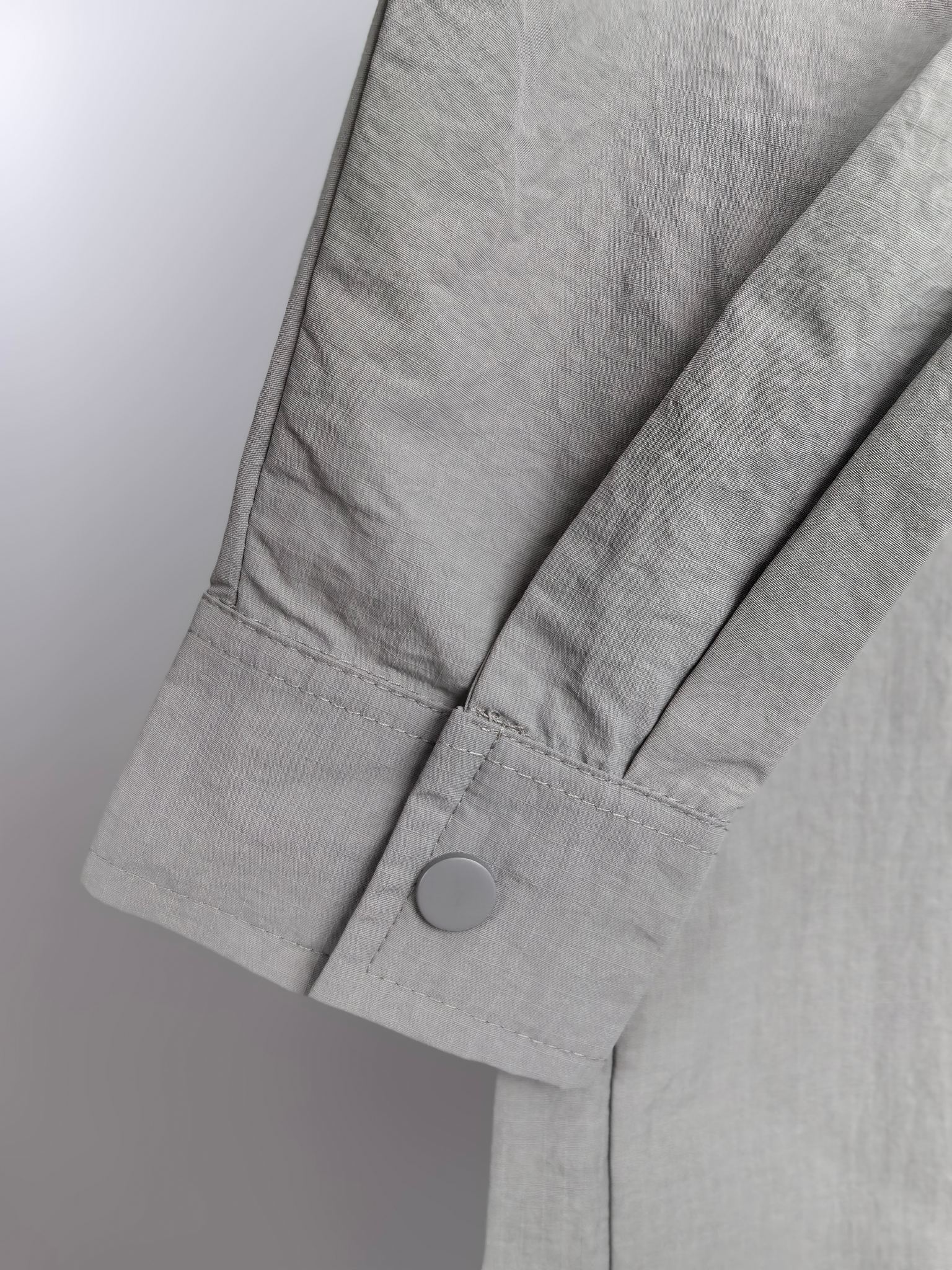 Gray jacket sleeve with buttoned cuff and structured seam detail