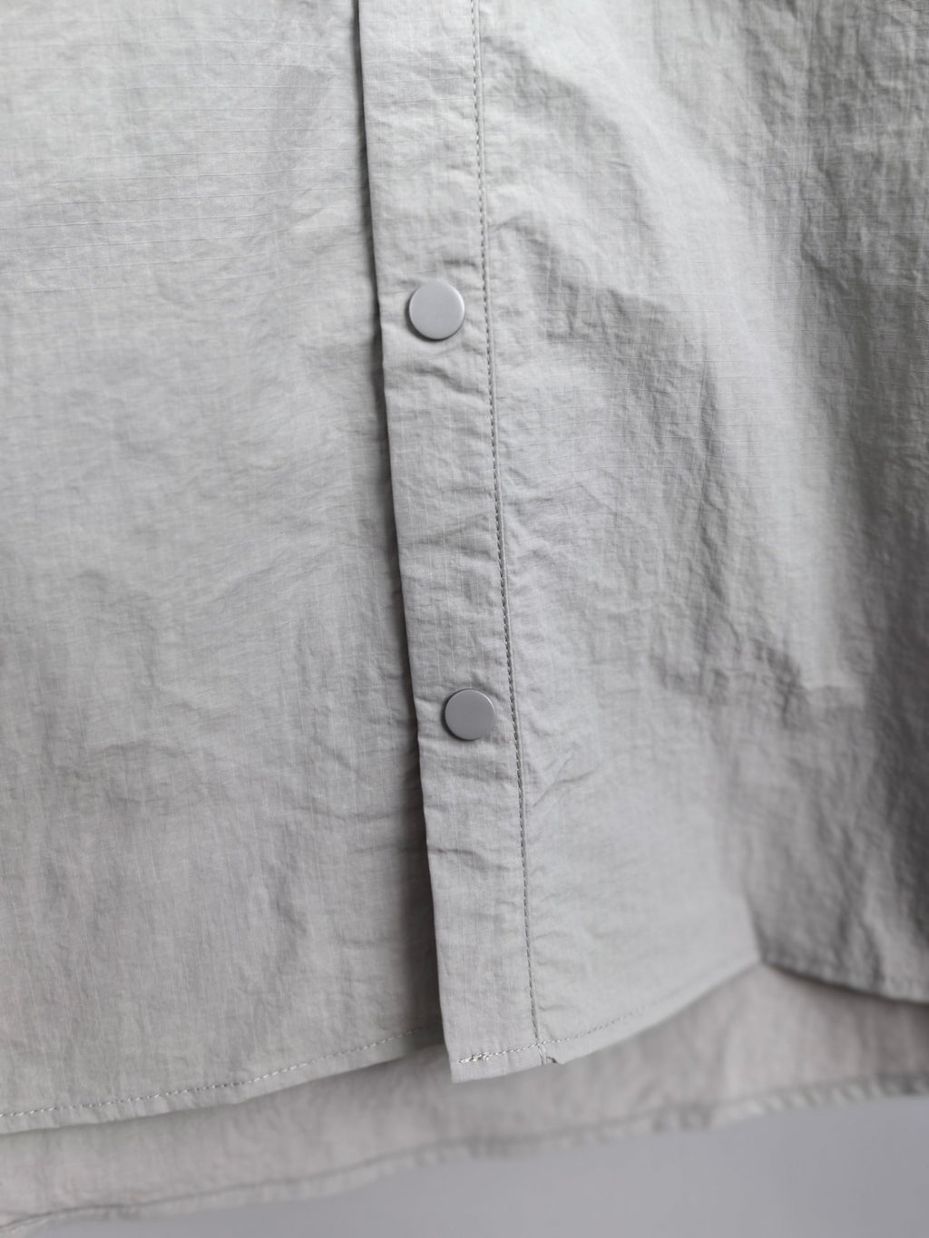 Gray jacket front panel with two visible metal snaps