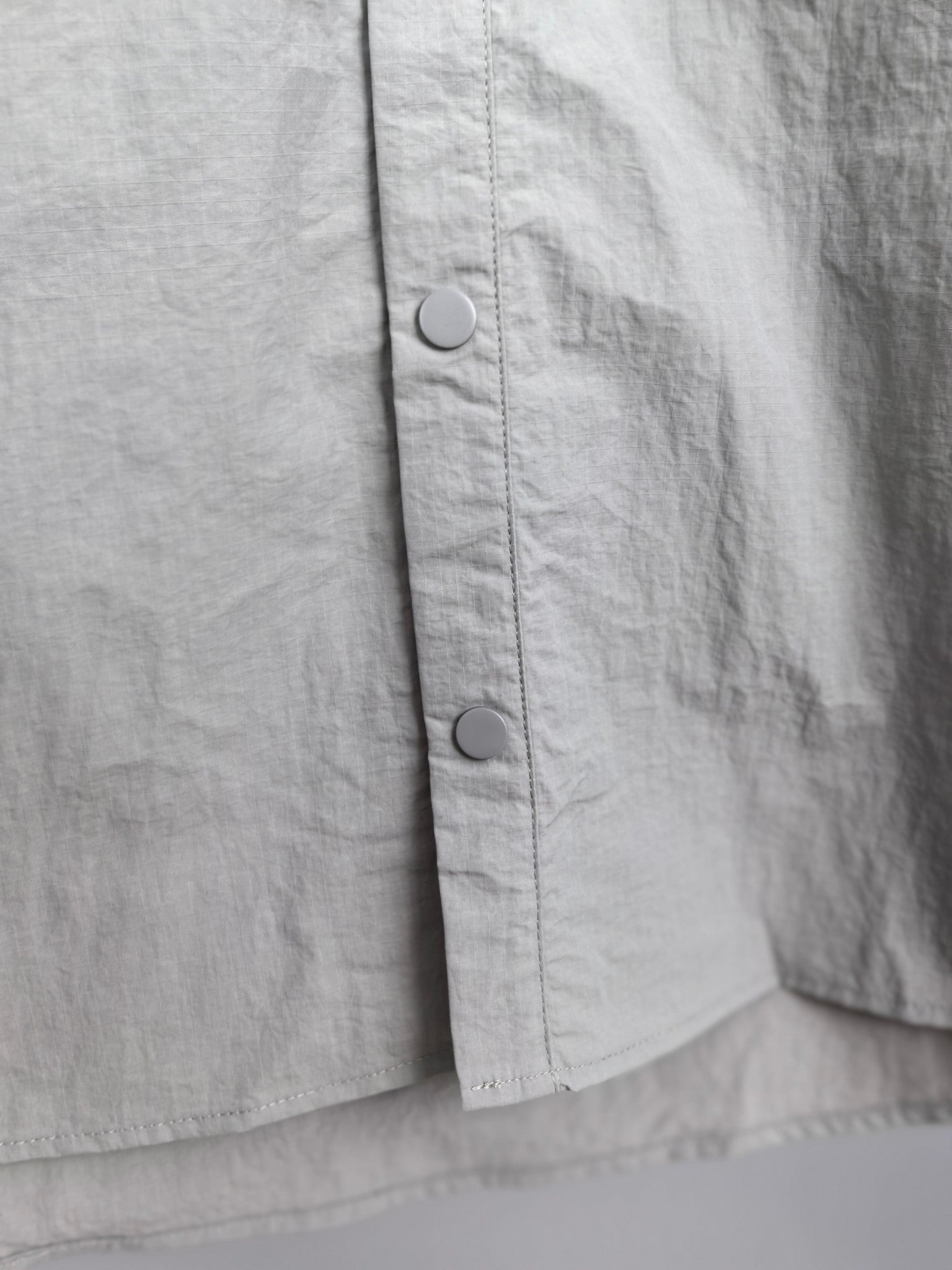 Gray jacket front panel with two visible metal snaps