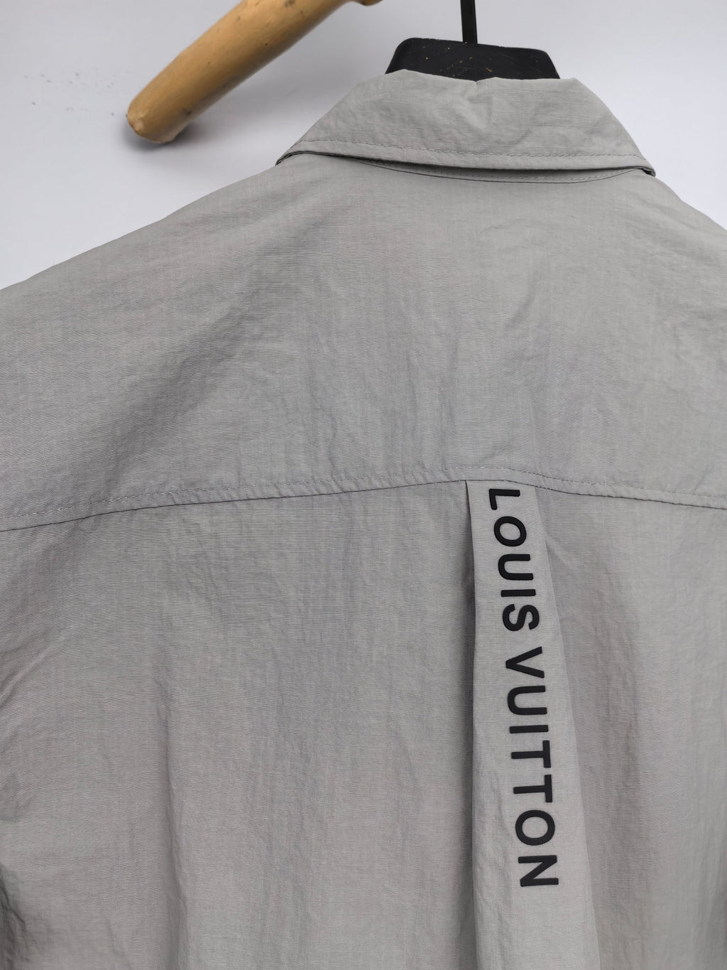 Gray jacket back with vertical "LOUIS VUITTON" text