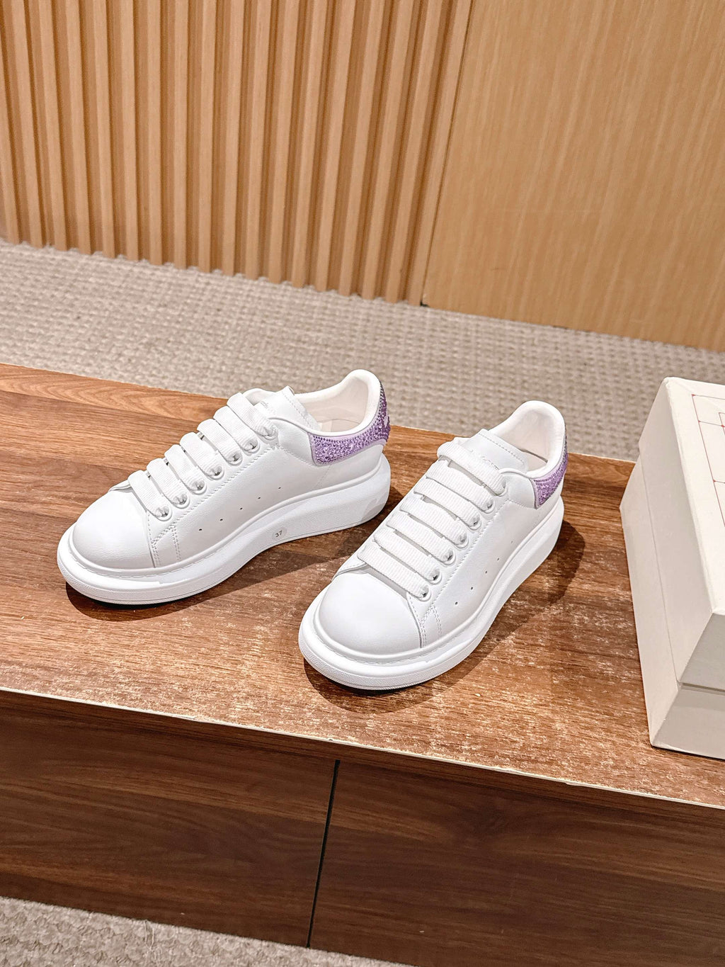 White lace-up sneakers with purple side panel accents on low sole