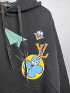 Black hoodie close-up with large front cartoon and emblem graphic