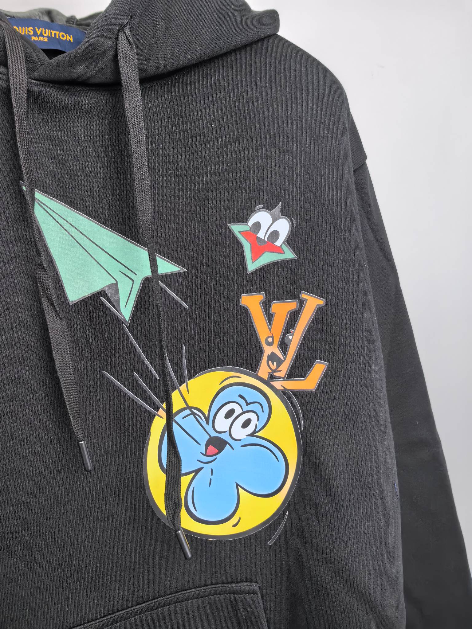 Black hoodie close-up with large front cartoon and emblem graphic