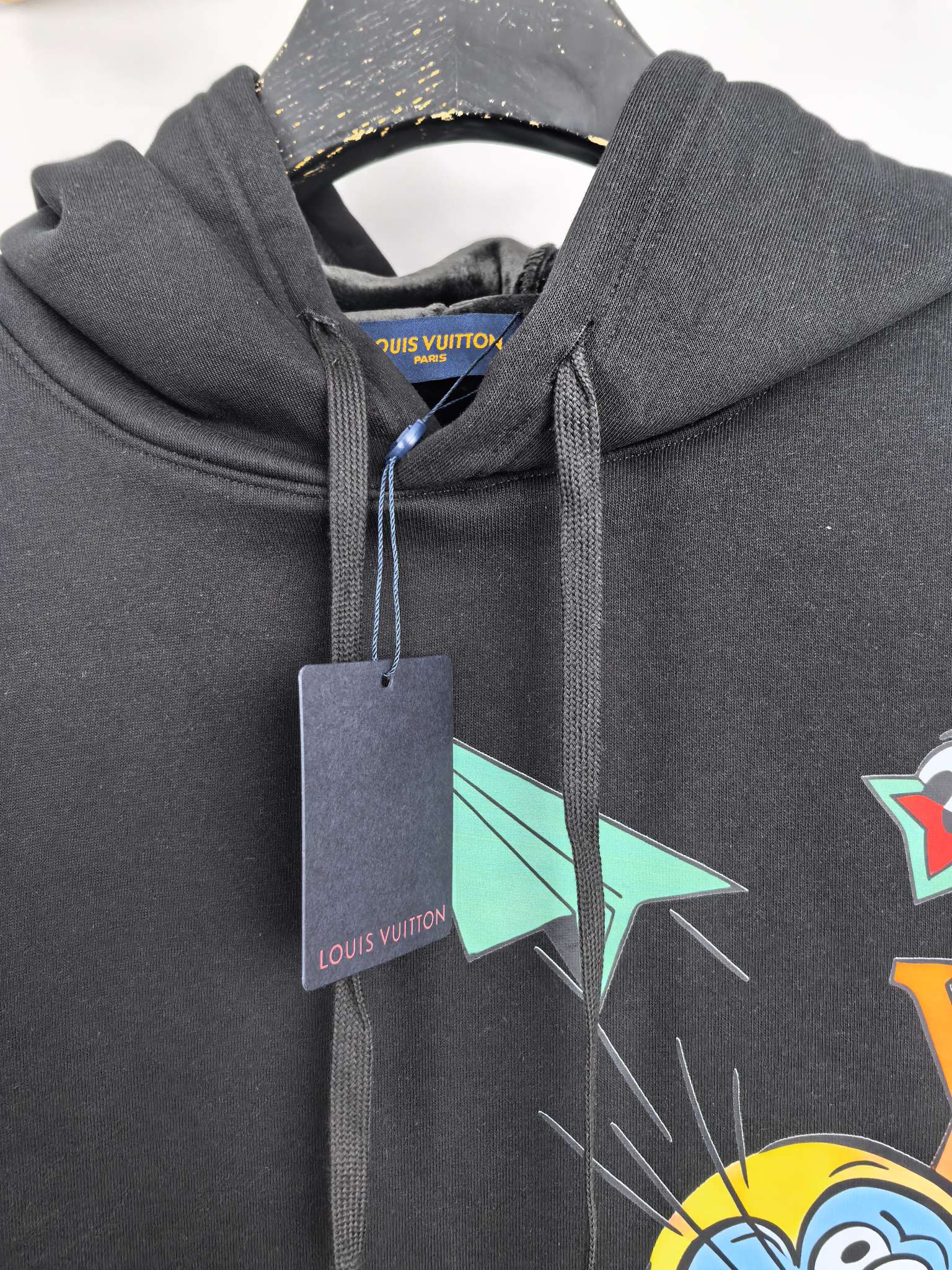 Black hoodie close-up with colorful paper-plane and cartoon graphic