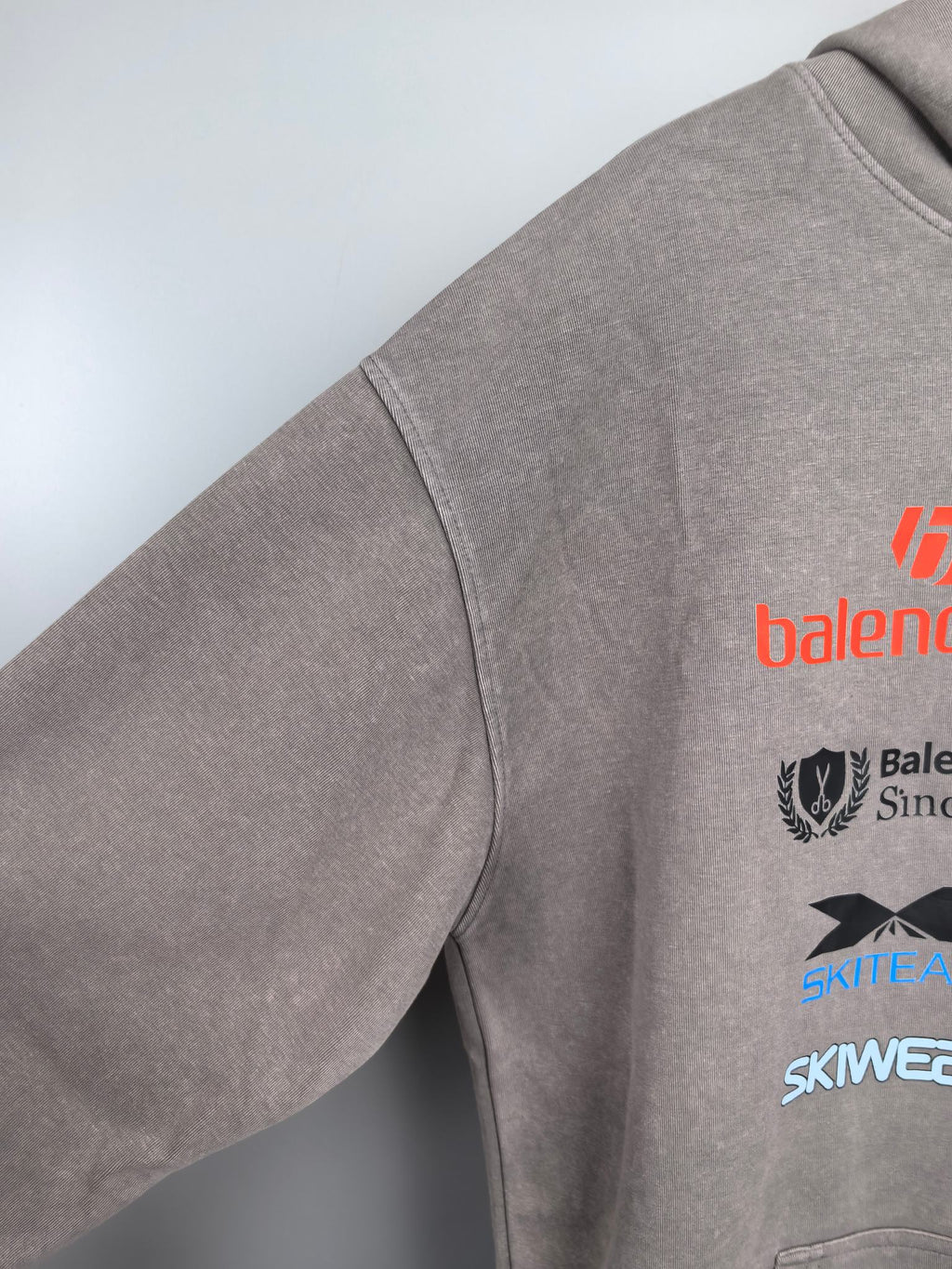 Gray pullover hoodie sleeve with partial logo print and crew neckline