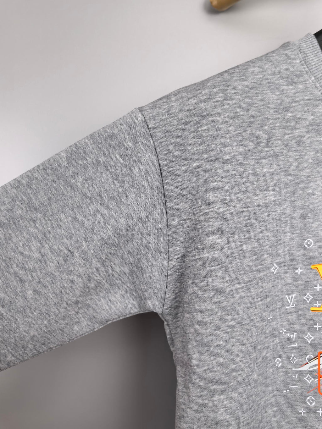 Gray long-sleeve sweatshirt sleeve with side seam and partial graphic print