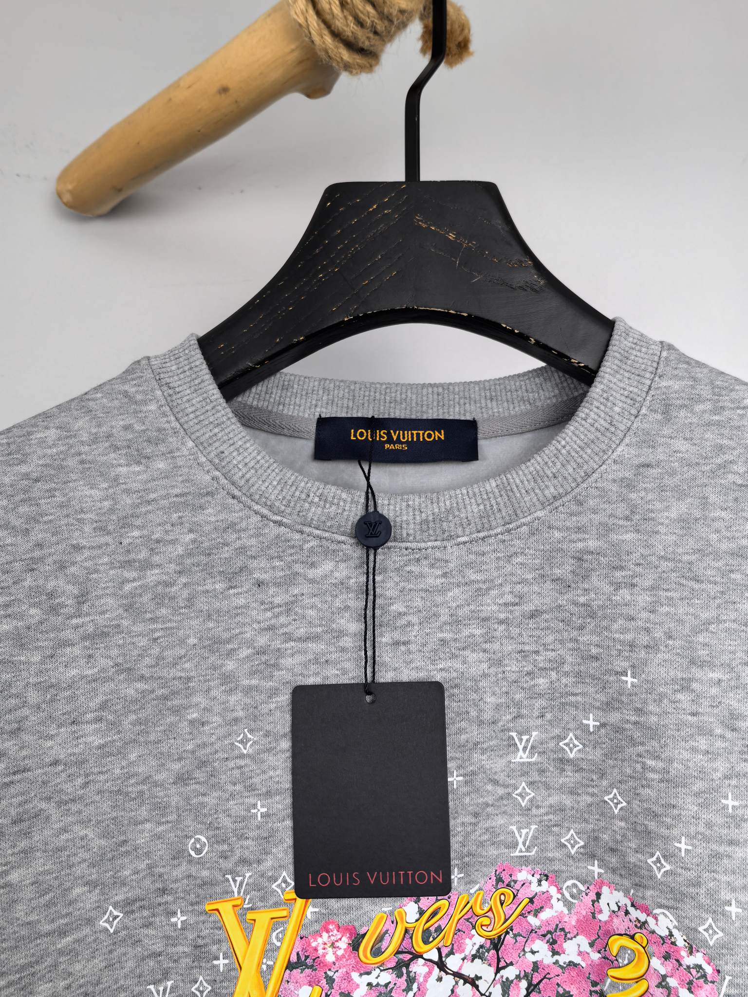 Gray sweatshirt neckline with attached tag and colorful LV graphic detail