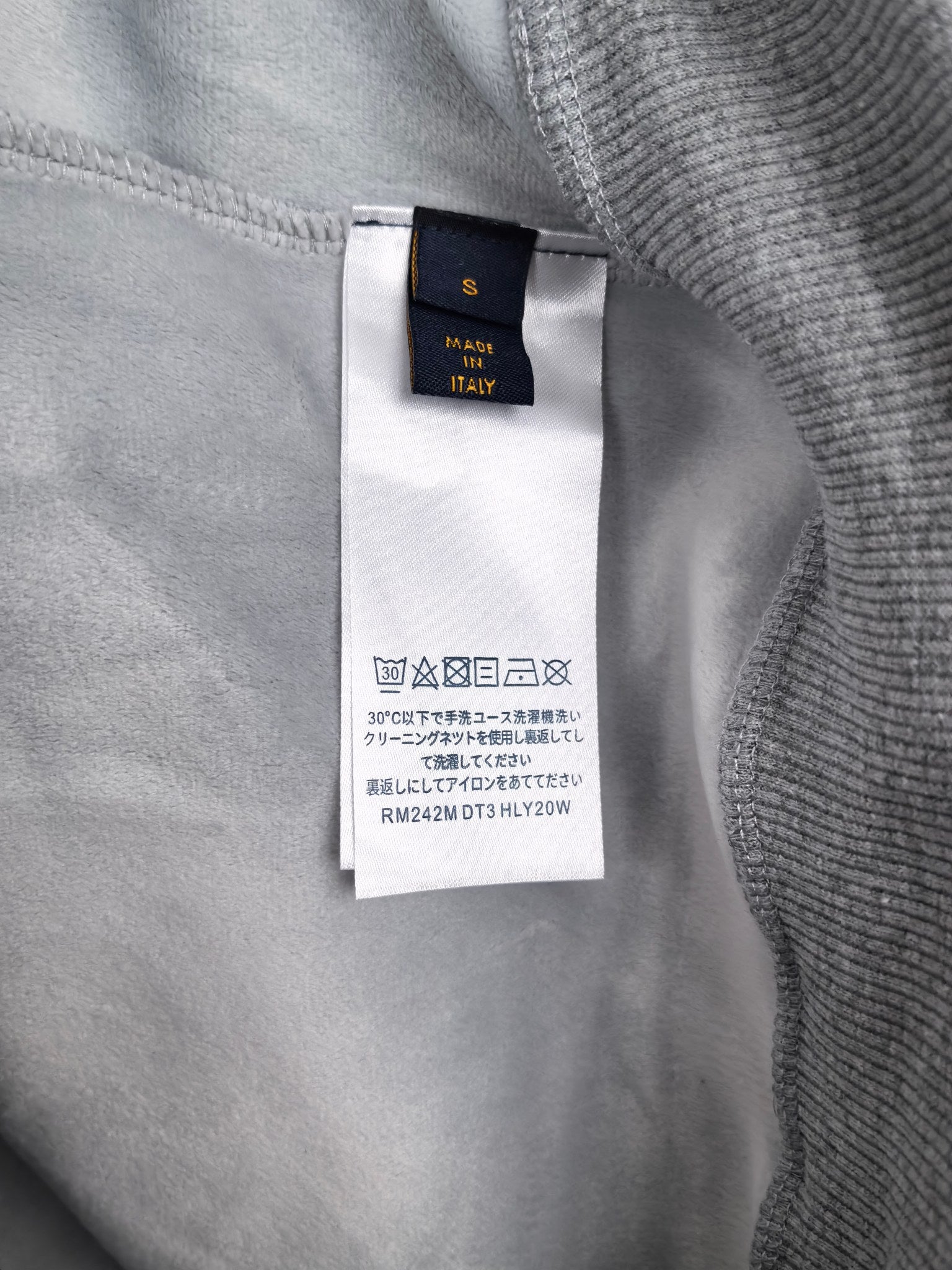 Interior neck label on gray sweatshirt with care information tag