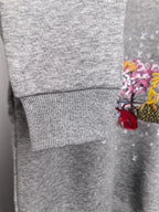 Gray ribbed sleeve cuff detail with partial colorful graphic on the shirt