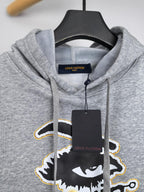 Gray kids hoodie detail with hood opening, Louis Vuitton logo tag, and drawstrings