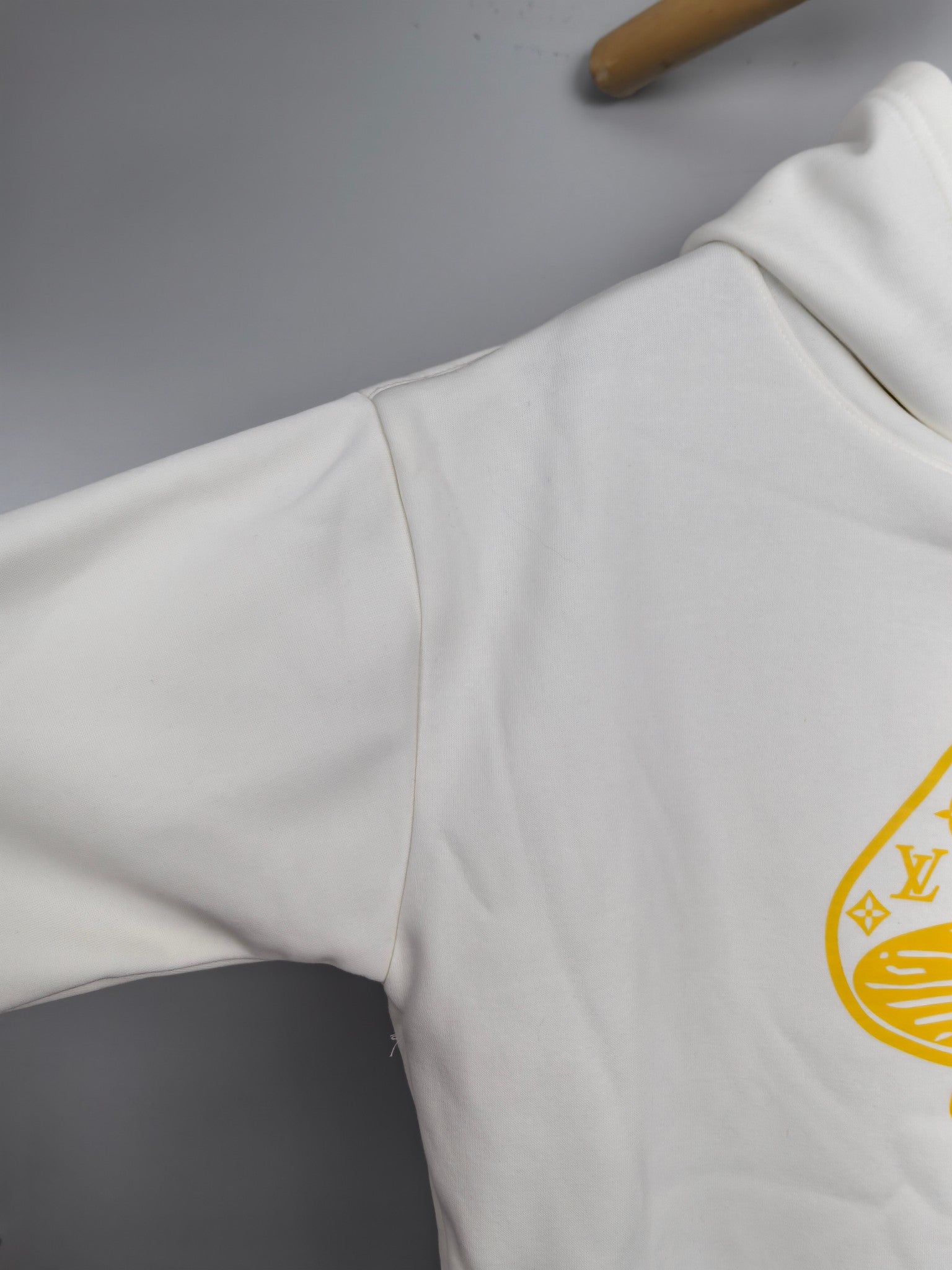 White hoodie side panel with partial gold logo print