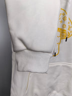 White hoodie lower panel with ribbed sleeve cuff and small gold logo print