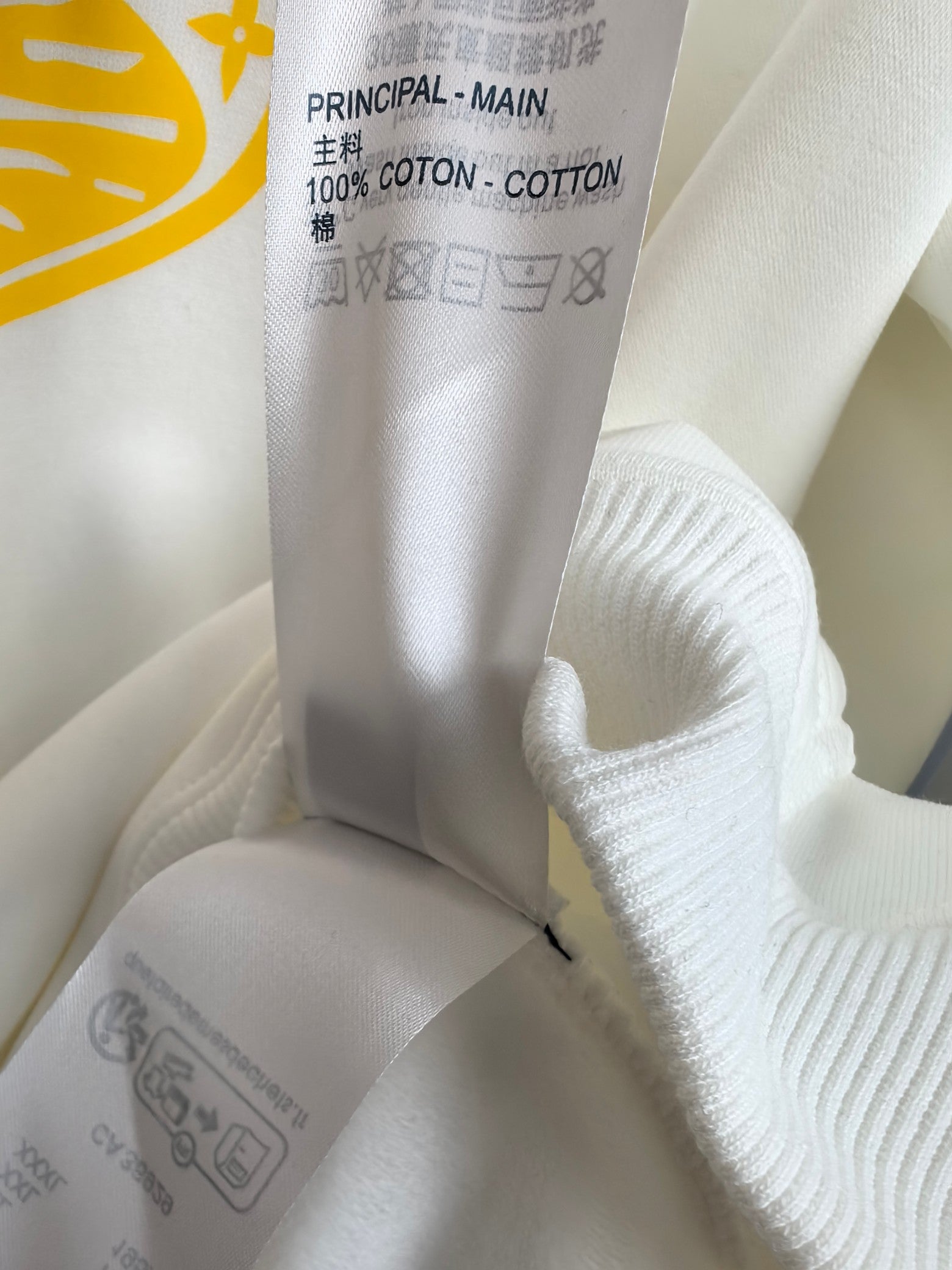 White hoodie fabric tag with text and knit ribbed cuff detail