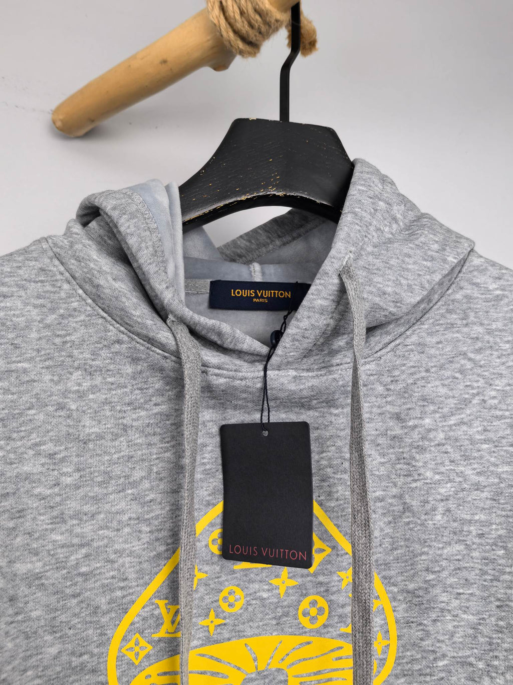 Gray hoodie hood with yellow graphic print and black neck hang tag