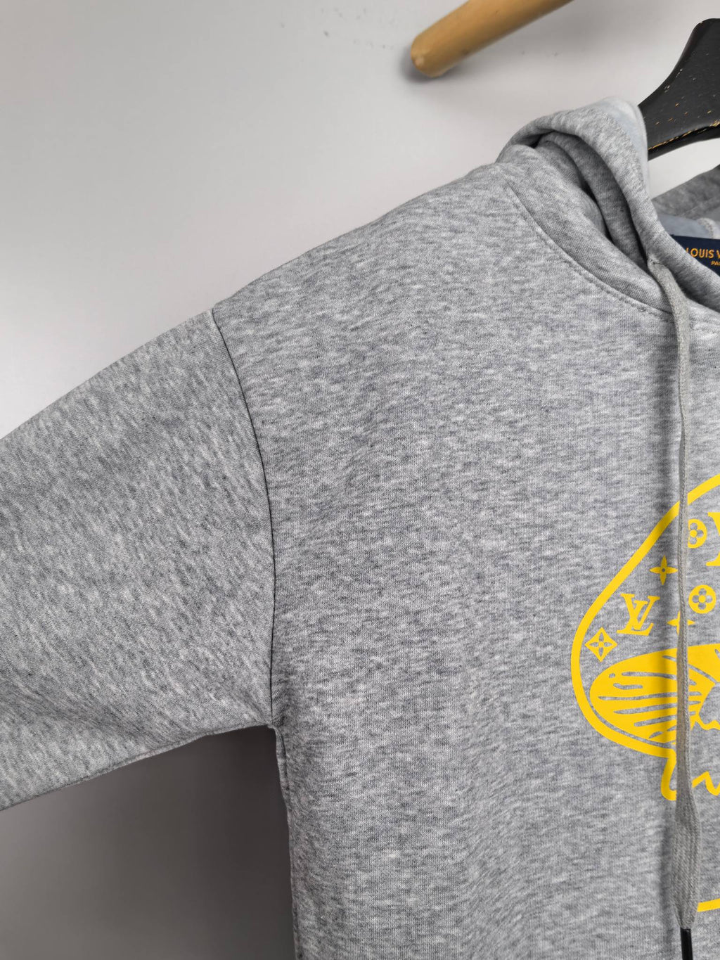 Gray hoodie sleeve with partial yellow graphic print