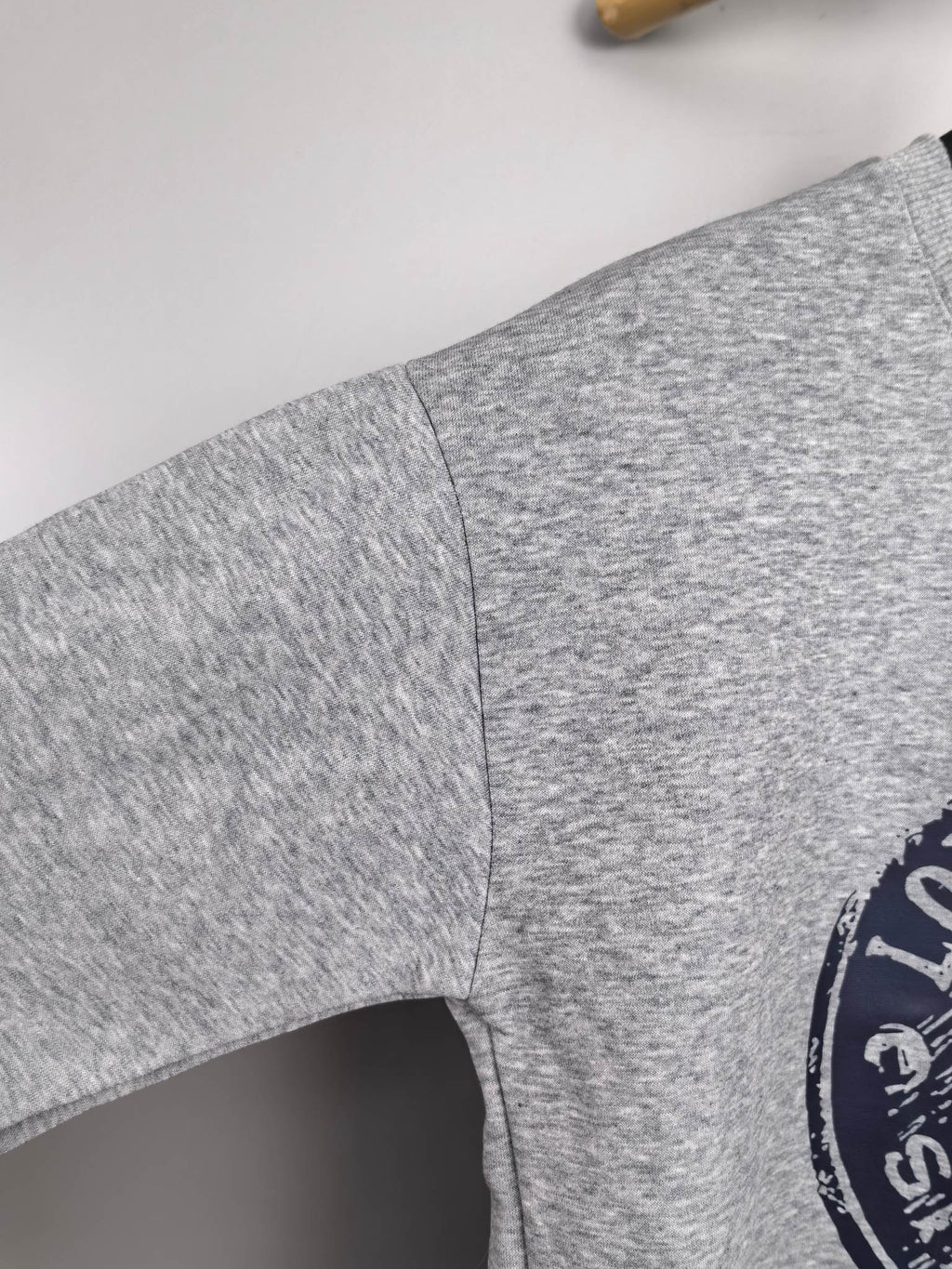Grey sweatshirt sleeve with side seam and partial Louis Vuitton Voyage logo