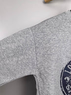Grey sweatshirt sleeve with side seam and partial Louis Vuitton Voyage logo