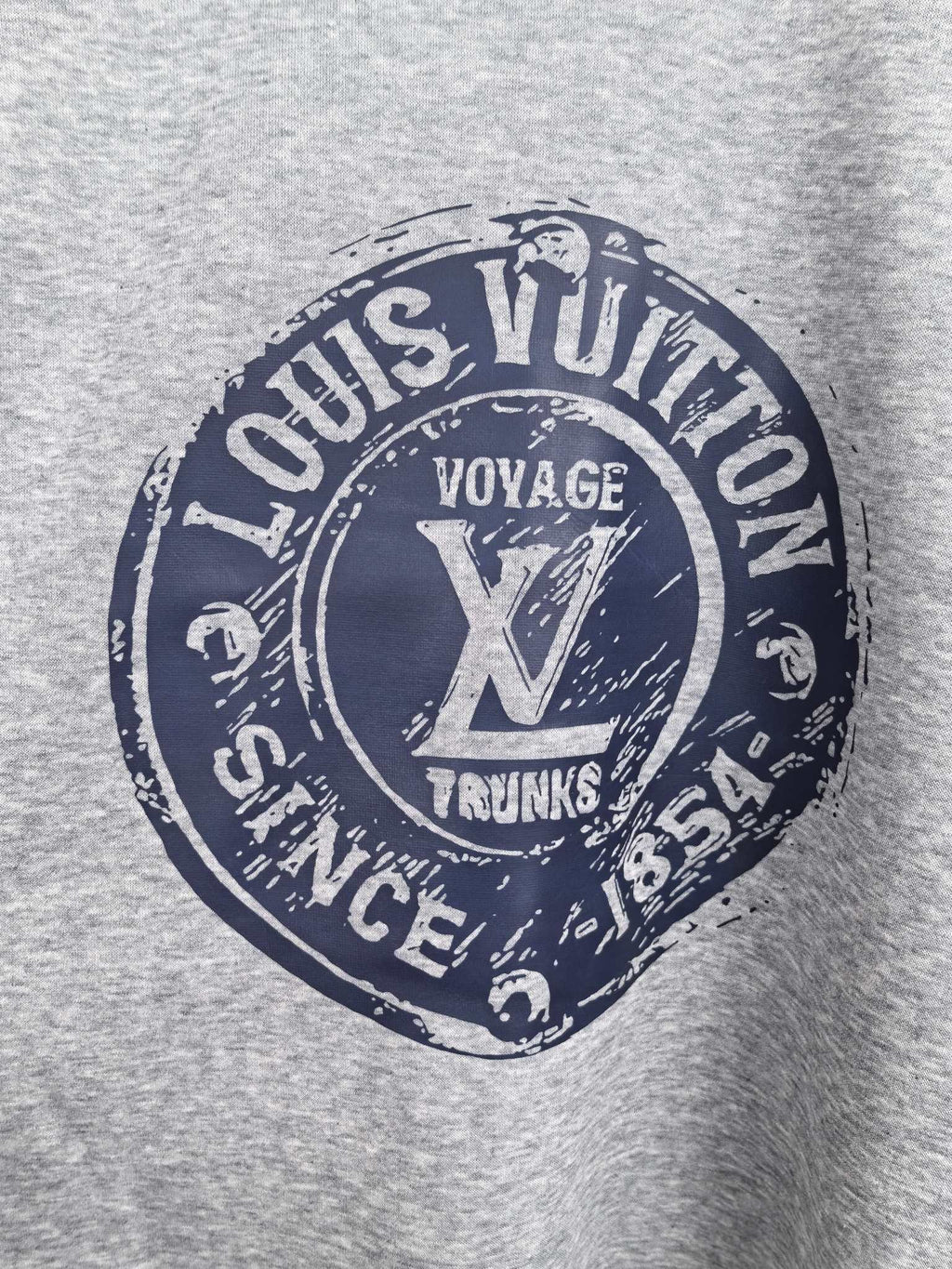 Grey sweatshirt front featuring Louis Vuitton Voyage Trunks circular graphic