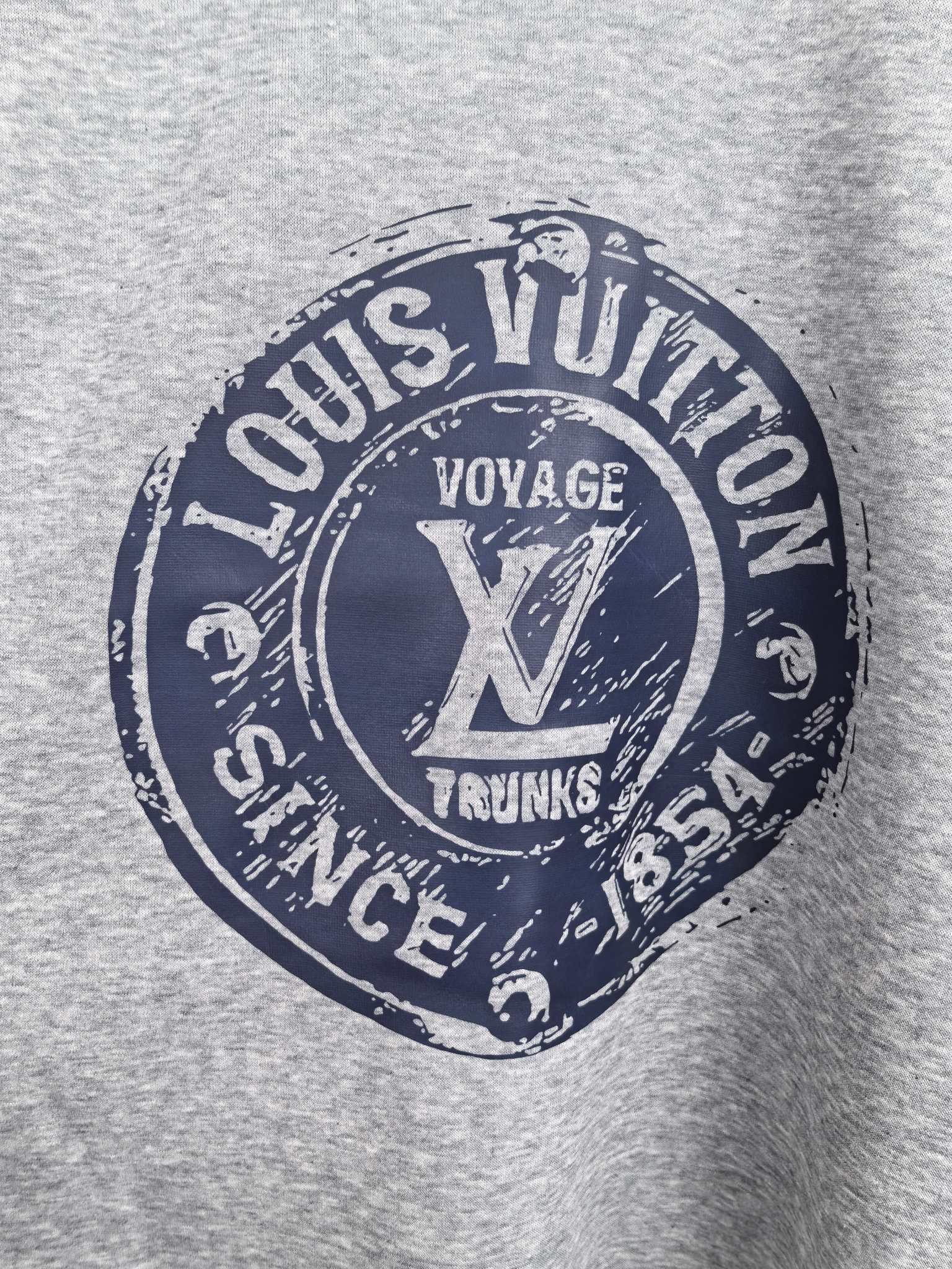 Grey sweatshirt front featuring Louis Vuitton Voyage Trunks circular graphic
