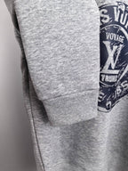 Grey sweatshirt sleeve cuff detail with partial Louis Vuitton Voyage logo