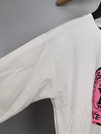 White long-sleeve sweatshirt sleeve with partial pink logo print