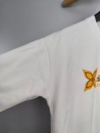 White sweatshirt sleeve with partial orange Louis Vuitton-style logo