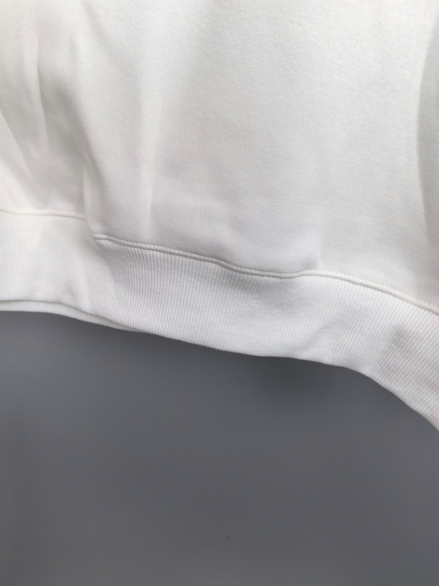 White sweatshirt ribbed hem and stitched seam close-up